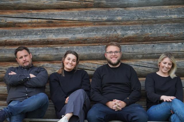 Foto av de ansatte sittende foran en vegg